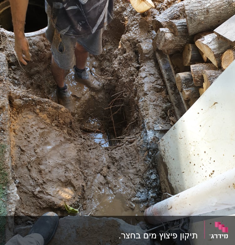 אדם עובד בבור בוץ עם צינור פלסטיק